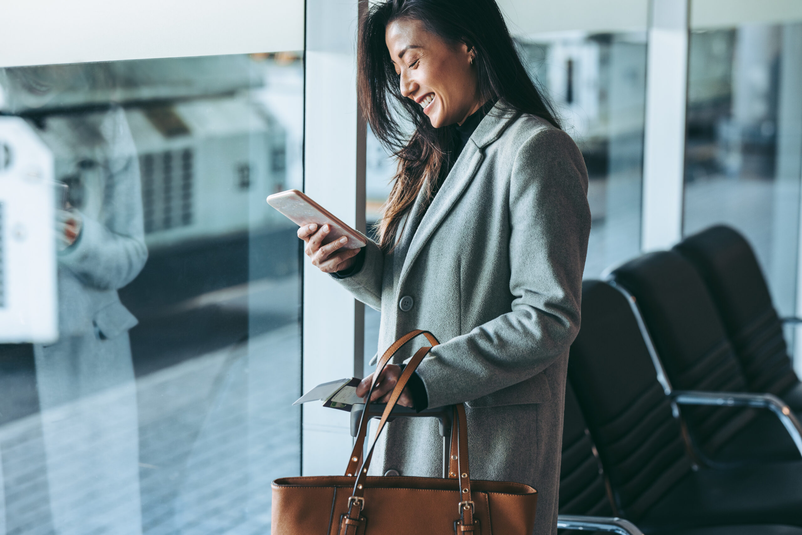 Corporate traveller staying connected on phone while waiting for the plane